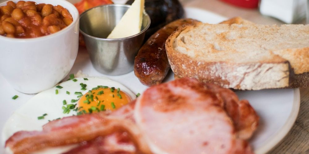 A cooked breakfast: bacon, sausage, fried egg, beans and toast.