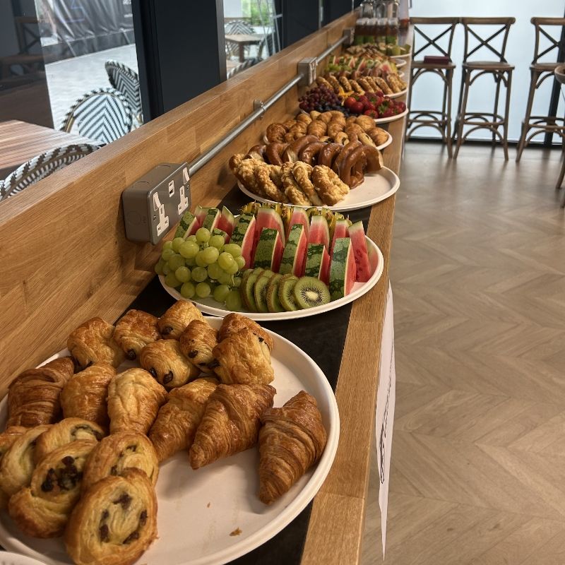 Croissants, pastries and plates of fruit laid out along the bistro's wooden counter for an event.